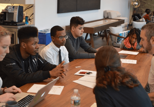 Students and adults meeting at a conference table