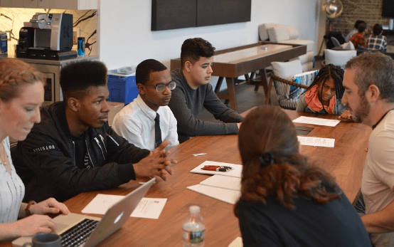 Students and adults meeting at a conference table