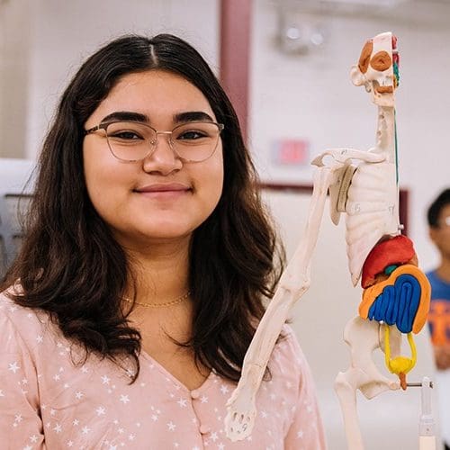 Young woman in a science classroom with model of internal anatomy