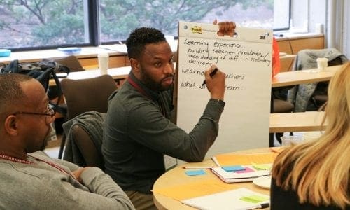 Black male educator with flipchart and colleagues