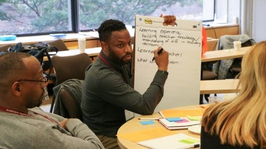 Black male educator with flipchart and colleagues