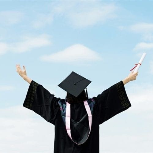 back of graduate in gown, arms outstretched