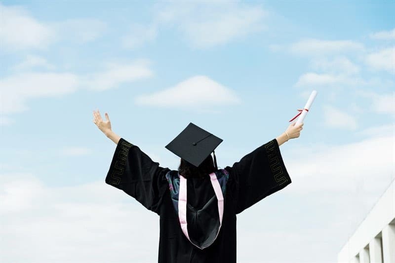 back of graduate in gown, arms outstretched