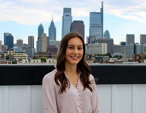 Sideways picture of new CAP Coordinator, Rachel Gerberick, behind Philadelphia's skyline.