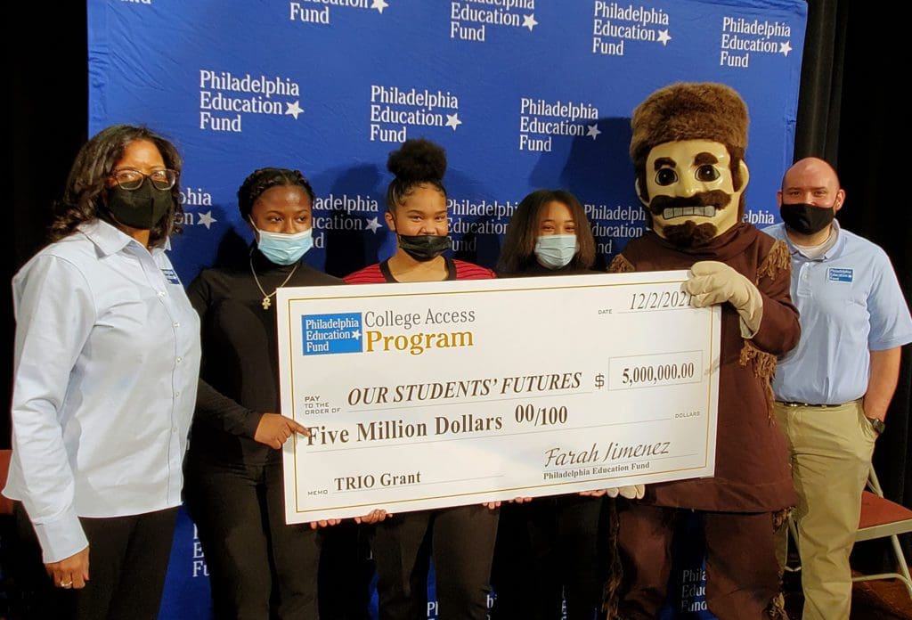 People standing with giant check and school mascot.