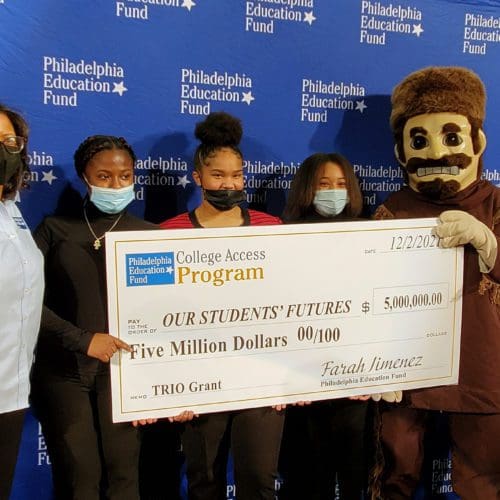 People standing with giant check and school mascot.