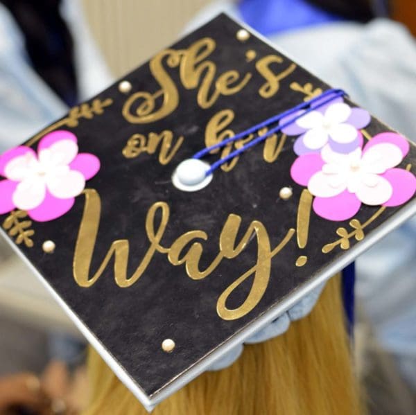 Graduation mortarboard with decorations and words "She's on her way."