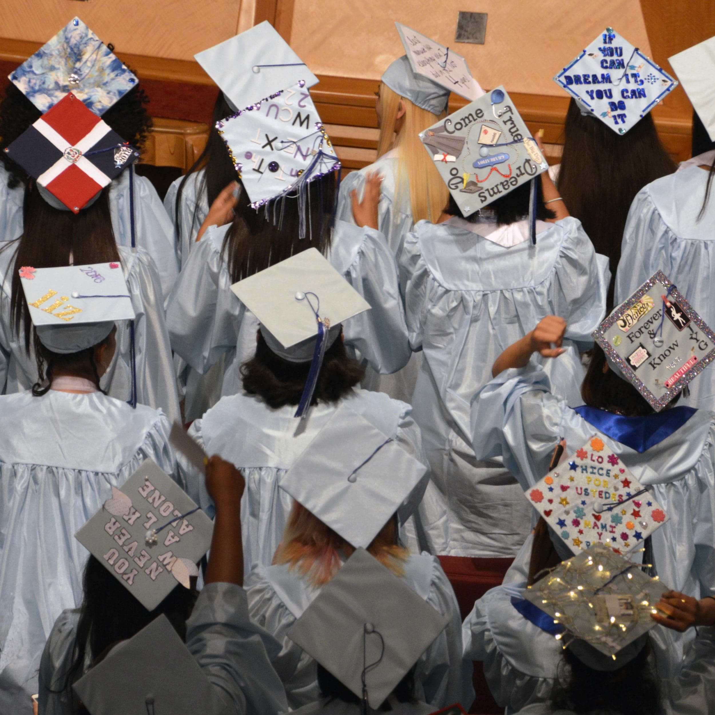 Students' graduation caps very decorated in a view from behind.