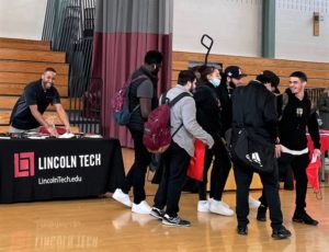 Group of high school students leaving a college fair in a high school gym.