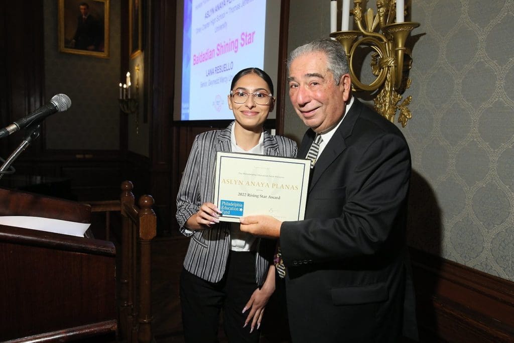 Young woman accepting award certificate from older man at an event.