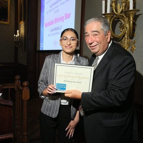 Young woman accepting award certificate from older man at an event.