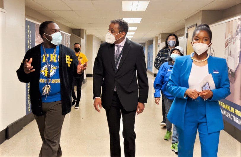 School staff in conversation with Dr Tony Watlington. while walking down school hallway.